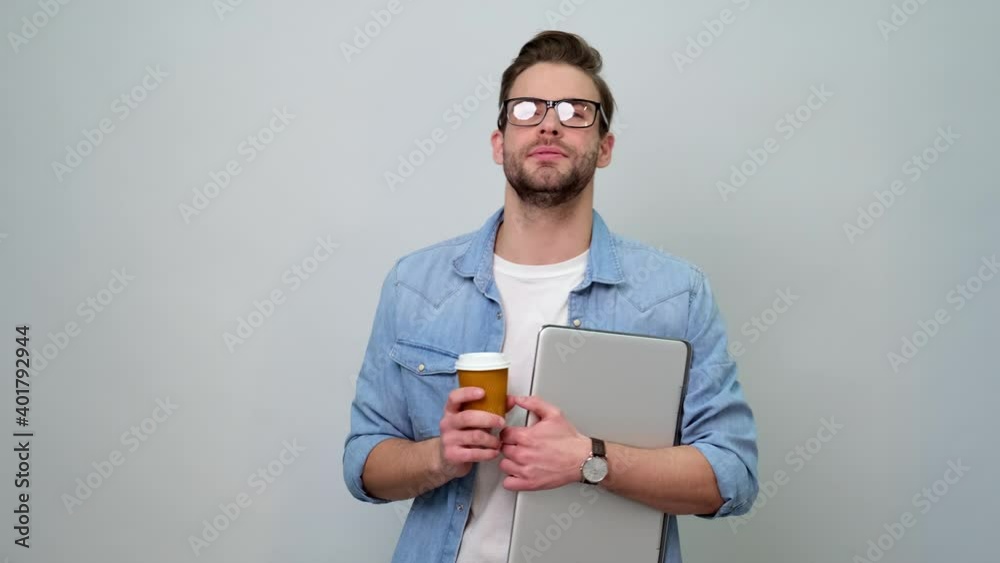 Man Drinking Coffee and holding Laptop while standing over light grey background