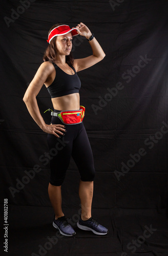 Beautiful redhead girl in jogging uniform posing in studio on black background