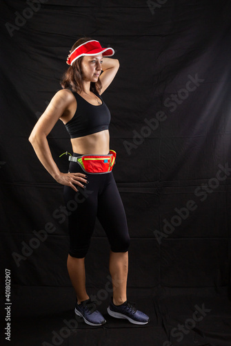 Beautiful redhead girl in jogging uniform posing in studio on black background