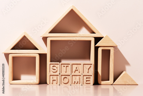 Message Stay Home made of wooden letters and wooden abstract houses, concept of quarantine photo