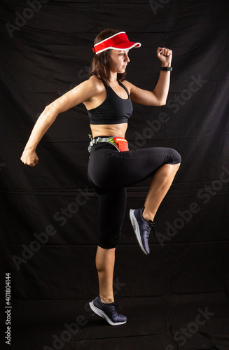 girl in red jogging uniform runs in the studio on a black background