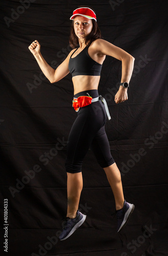 girl in red jogging uniform runs in the studio on a black background