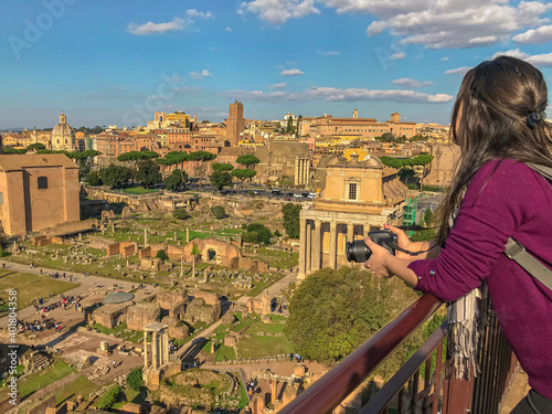 tourist woman looking at the Roma Forum on a sunny day holding photo camera photo