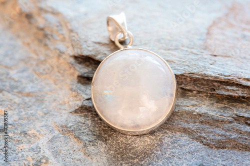 Sterling silver pendant with mineral moon stone gemstone on rocky background photo