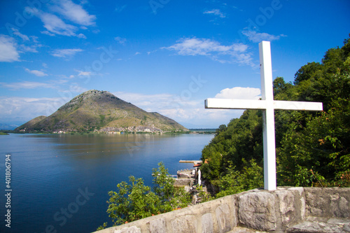 Cross at the old church above beautiful lake and mountains