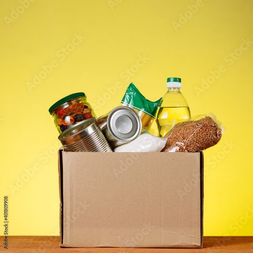 Food Donation concept. Donation Box With food For Donation On Yellow. Assistance To The Elderly In The Context of The Coronavirus Pandemic. square image
