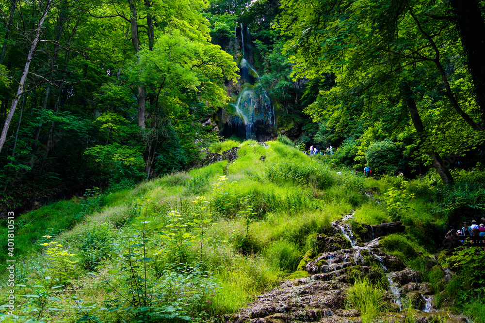 Beautiful view of the Uracher Waterfall surrounded by fresh green forest.
