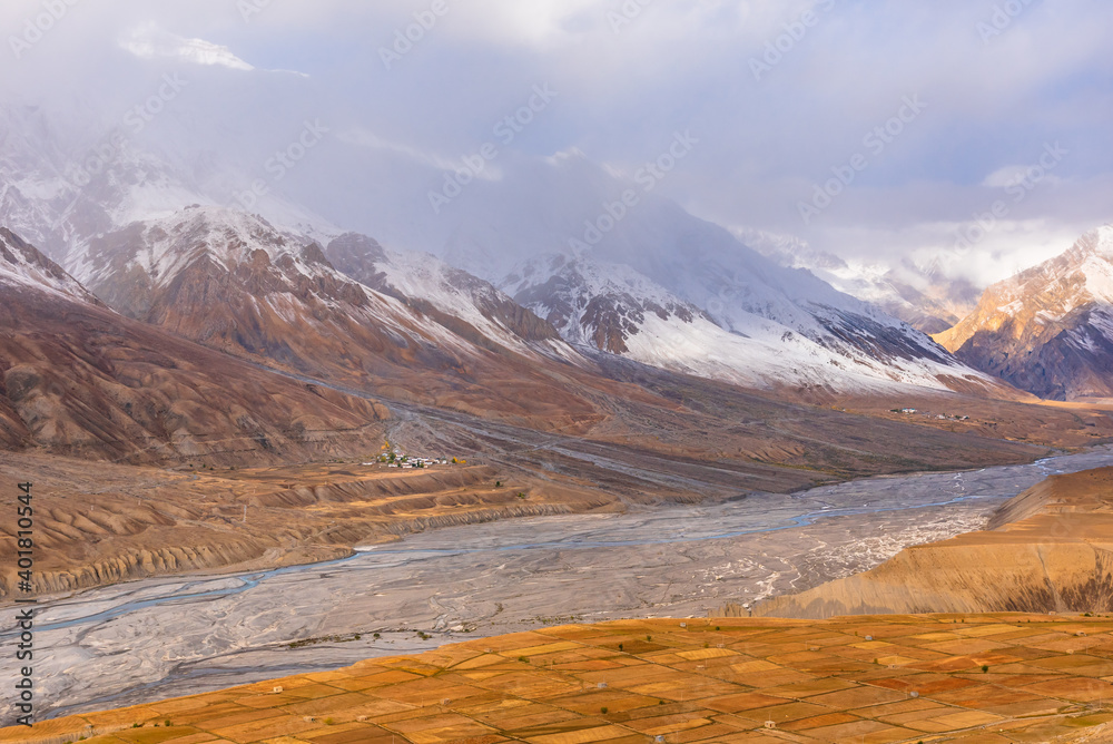 Serene Landscape of Spiti river valley with agriculture fields and snow capped mountains in background during sunrise near Kaza town in Lahaul and Spiti district of Himachal Pradesh, India.