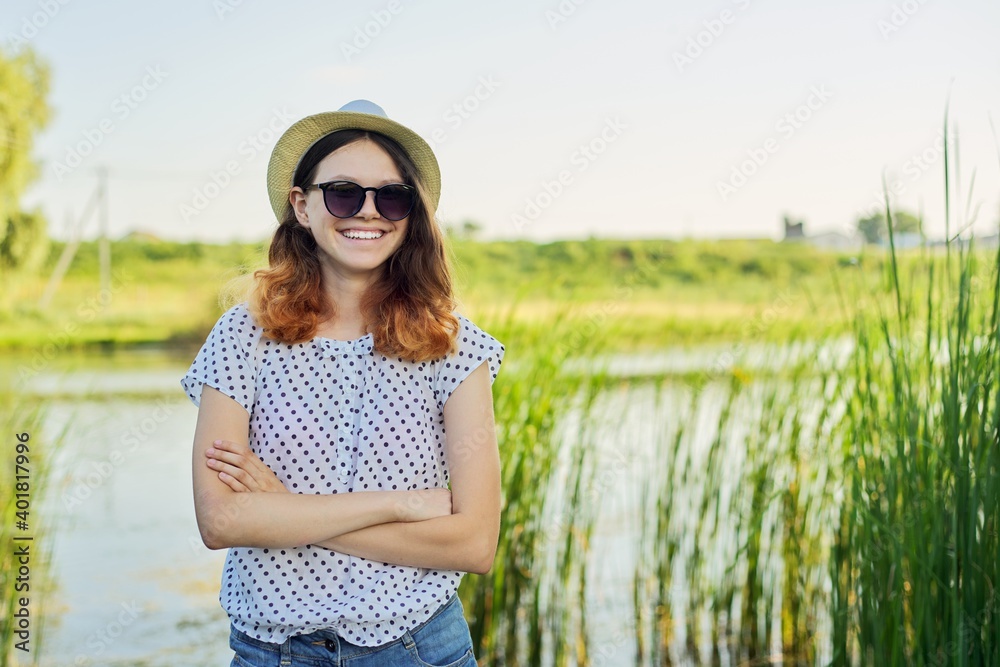 Outdoor country portrait of teenage girl in hat sunglasses near pond in the reeds Outdoor country portrait of teenage girl in hat sunglasses near pond in the reeds