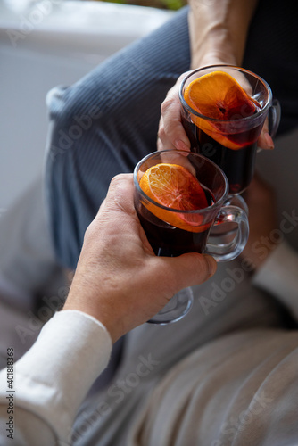 female and male hands holding glasses of mulled wine