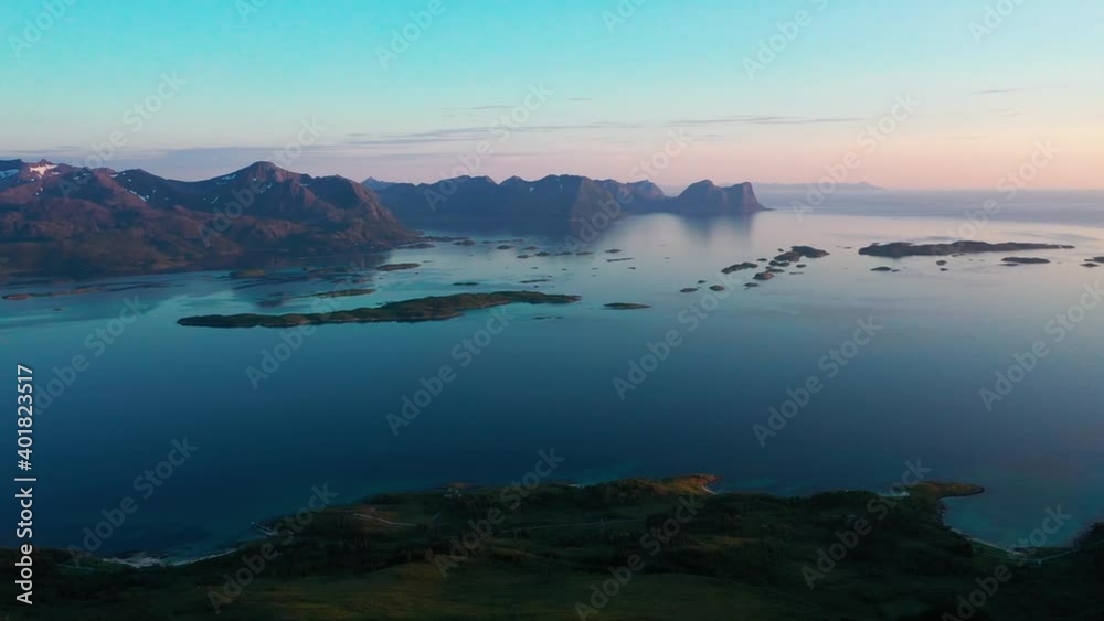 Aerial view of small islands in the Bergsoyan archipelago, with mountain range and Norwegian sea background, in Senja, Norway - Descending, drone shot Aerial view of small islands in the Bergsoyan archipelago, with mountain range and Norwegian sea background, in Senja, Norway - Descending, drone shot