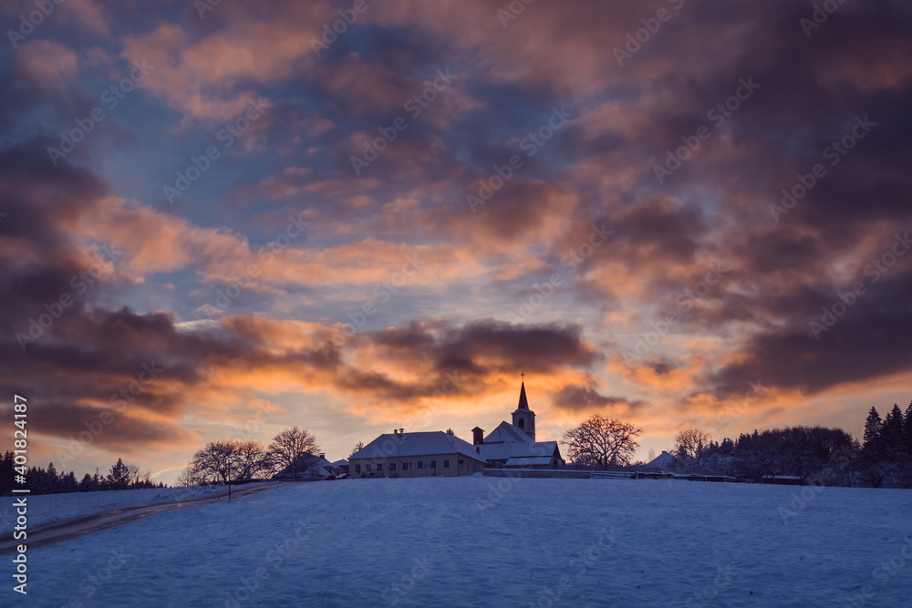 village with a church on a hill at sunset in winter, beautiful sky with illuminated clouds, Vezovata Plane, Czech republic