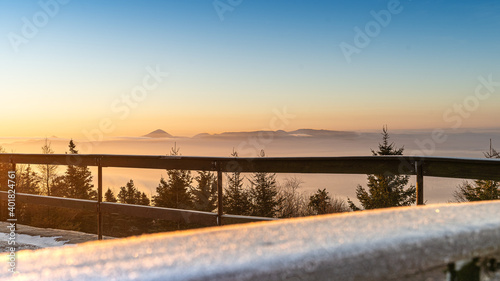 Sun rising above the land on blue sky. Nature background with sunny beams on the mountains