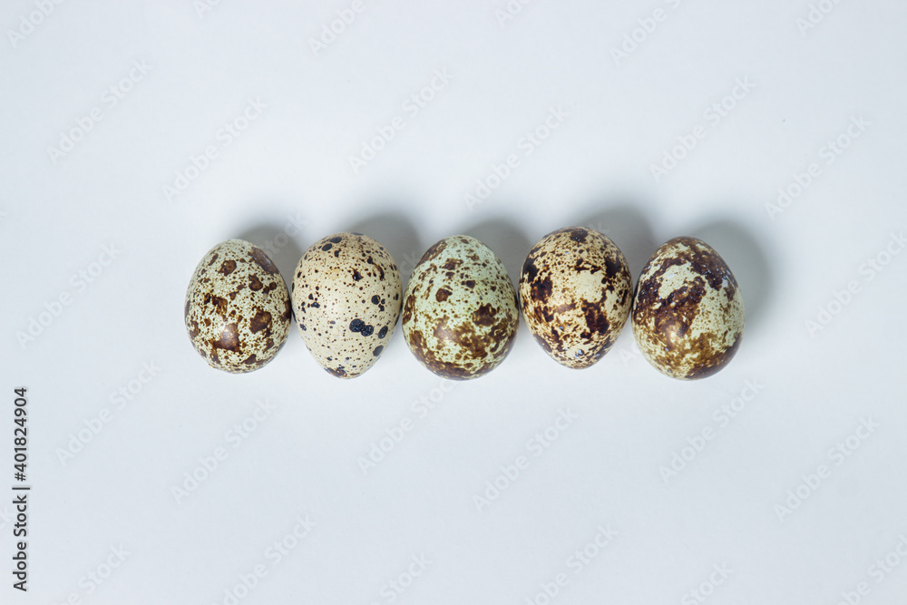 Quail eggs on a white background. Healthy eating. Quail eggs lie in a row Quail eggs on a white background. Healthy eating. Quail eggs lie in a row
