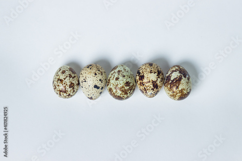 Quail eggs on a white background. Healthy eating. Quail eggs lie in a row © Ruzanna