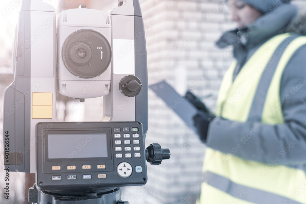 electronic total station in winter, a tool for performing geodetic, construction and cadastral works on the ground, selective focusing, tinting. electronic total station in winter, a tool for performing geodetic, construction and cadastral works on the ground, selective focusing, tinting.