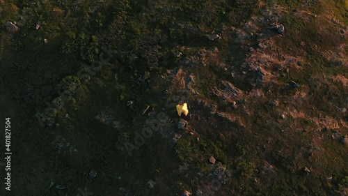 Aerial view towards a tent on a mountain during nightless night, in North Norway - descending, tilt drone shot photo