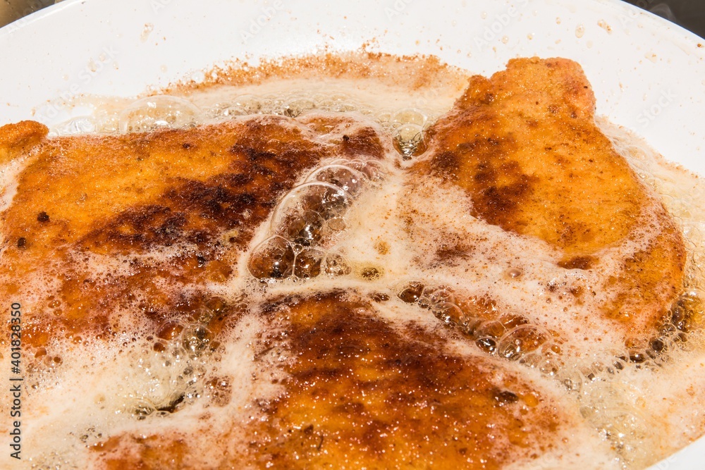 Wiener Schnitzel, frying in oil in a pan. Top view. Homemade