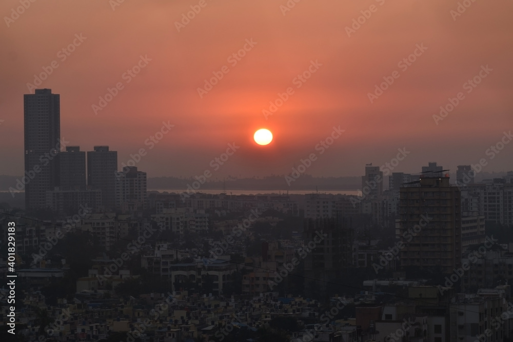 sun sets into arabian sea behind the silhouette city of mumbai borivali ,India ,Maharashtra. Beautiful Sunset with orange sky color .