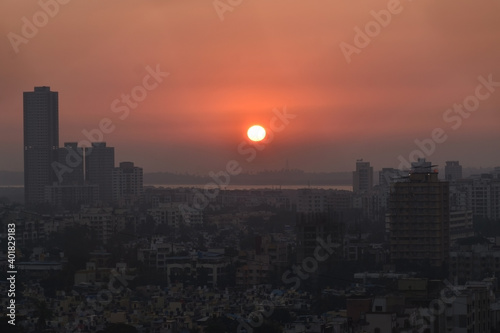 sun sets into arabian sea behind the silhouette city of mumbai borivali  India  Maharashtra. Beautiful Sunset with orange sky color .