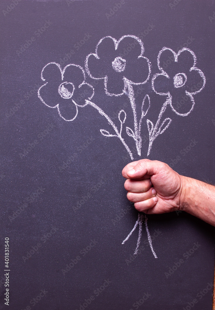 A man's hand holds flowers drawn on a chalkboard - obrazy, fototapety, plakaty 
