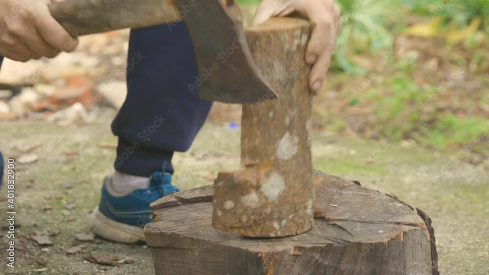 The footage shows chopping wood with an ax, on a stump. The wood is