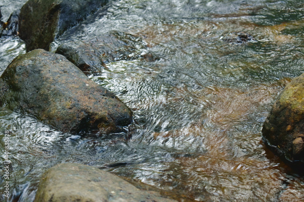 water falling on river pass rock and stone at waterfall in Thailand water falling on river pass rock and stone at waterfall in Thailand