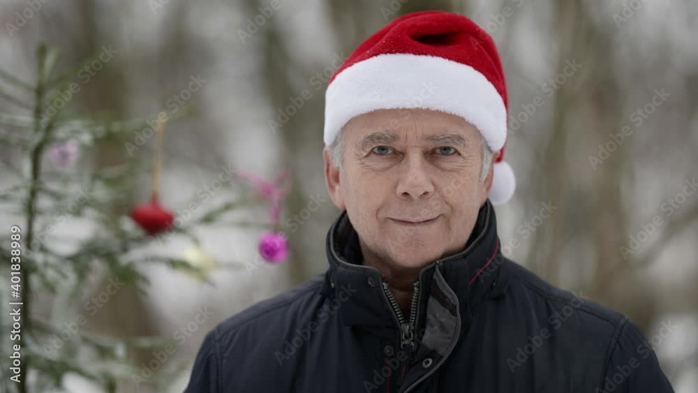 portrait of cute elderly man with red Santa hat in forest with Christmas tree portrait of cute elderly man with red Santa hat in forest with Christmas tree