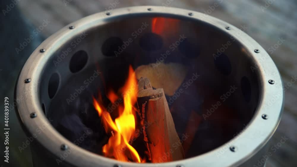 Luxury polished metal barrel with logs, fire and sparks on wooden porch Luxury polished metal barrel with logs, fire and sparks on wooden porch