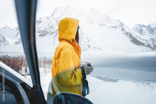 Alone brave woman traveler photographer looking away to winter mountains. Female photo explorer among winter landscape travel on car photo