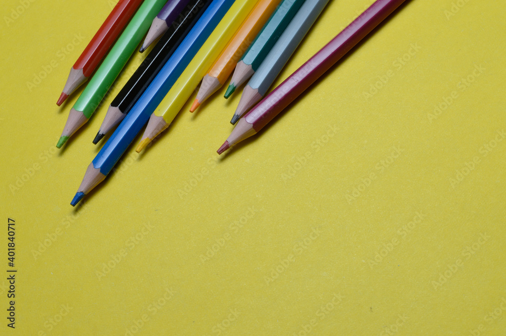 Obraz premium several multi-colored pencils lie on the yellow surface.