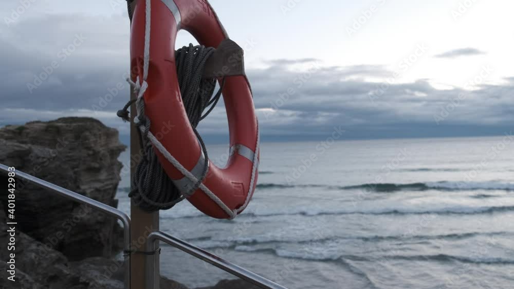aro salvavidas en playa y costa con viento y el mar de fondo

