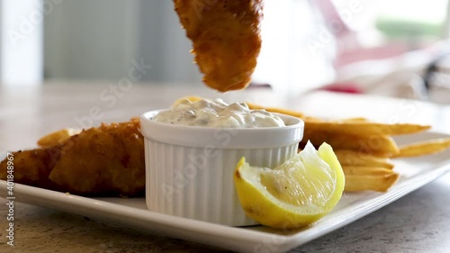 Dipping Fried Cod Into Tarter Sauce photo