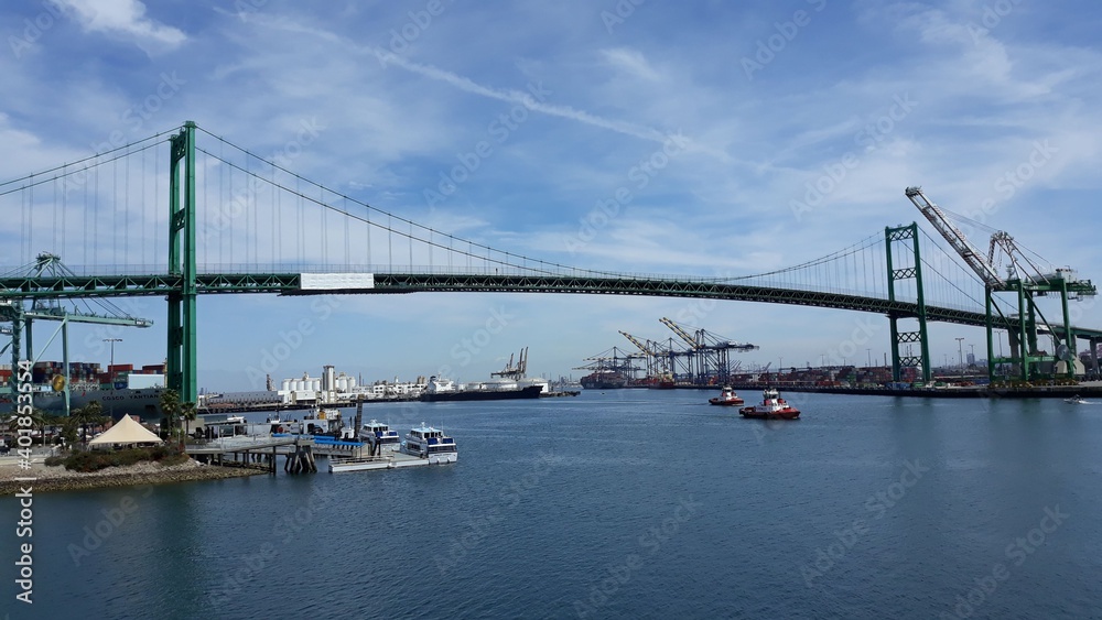 Los Angeles, California US: Vincent Thomas suspension bridge with the heavy cranes, cargo ships and small boats in San Pedro industrial and cruise ship port