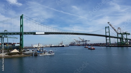Los Angeles, California US: Vincent Thomas suspension bridge with the heavy cranes, cargo ships and small boats in San Pedro industrial and cruise ship port