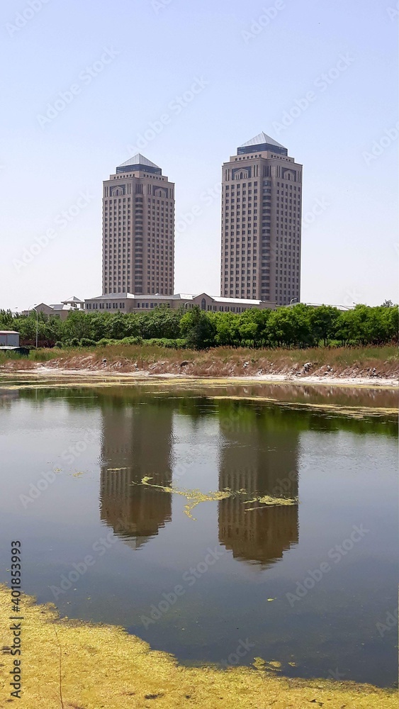 Tianjin, China - Two skyscrapers and their reflection in the river. Industrial area near cruise port. Typical architecture style from communist era
