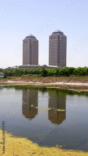 Tianjin, China - Two skyscrapers and their reflection in the river. Industrial area near cruise port. Typical architecture style from communist era © Pigeon