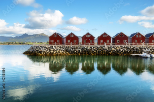 Traditional red wooden houses on the shore of Offersoystraumen fjord. Fantastic summer sunset on Vestvagoy island. Picturesque evening view of Lofoten Islands, Norway, Europe. Life over polar circle. photo