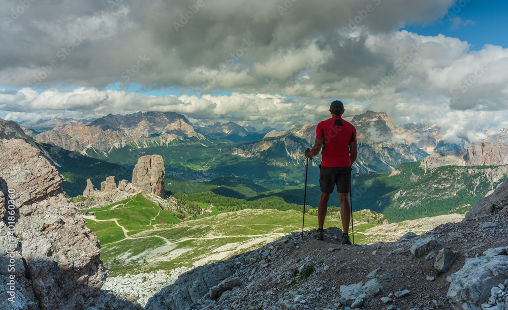 Person with trekking poles looking at mountains in Italian Dolomites