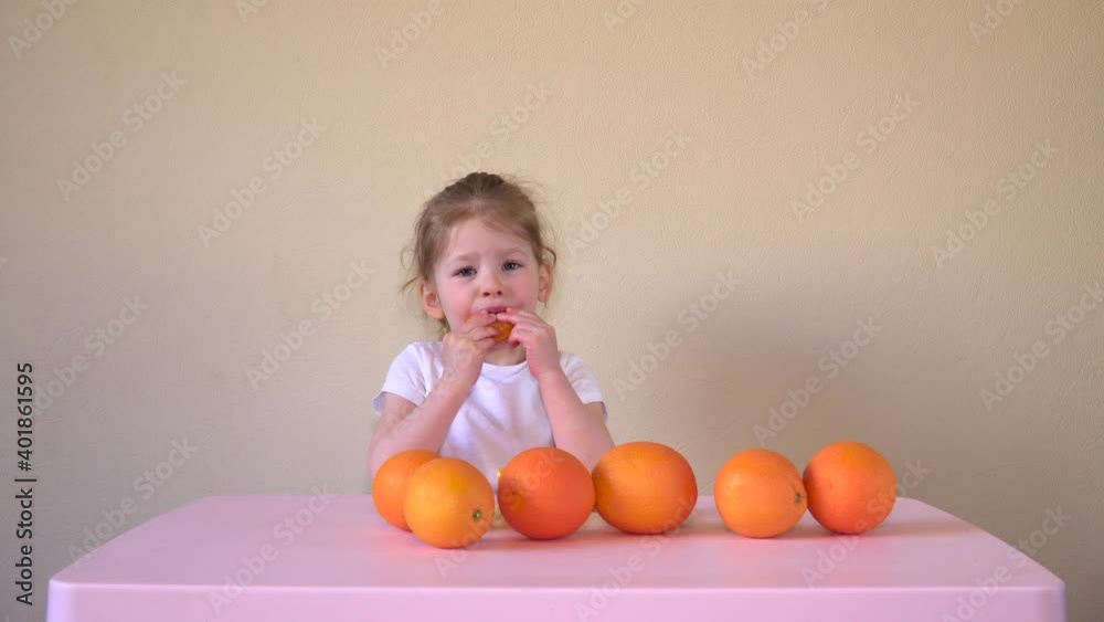 Cute little girl is eating an orange. Mandarin and baby. Food for children. Berries and fruits. High quality 4k footage Cute little girl is eating an orange. Mandarin and baby. Food for children. Berries and fruits. High quality 4k footage