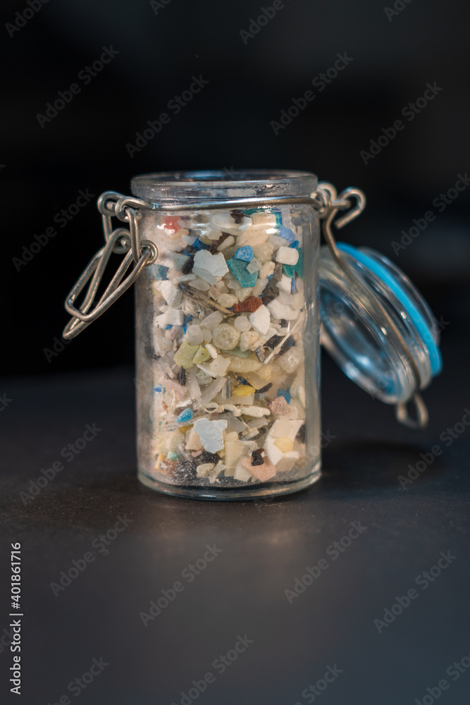Vertical stock photo of open glass jar filled with microplastics Vertical stock photo of open glass jar filled with microplastics
