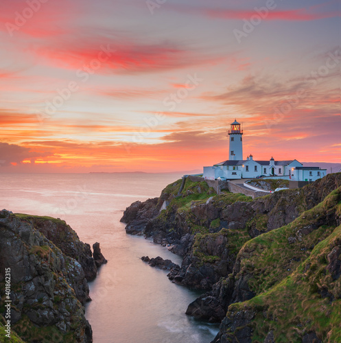 white lighthouse on the coast at sunset in Ireland © Roberti