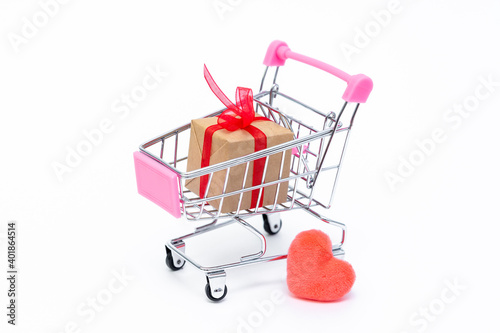Small grocery cart with gift boxes on white background. Give gifts with love on Valentine's Day, Christmas and birthday. Shopping online. Holiday sales and discounts. Retail and wholesale purchases