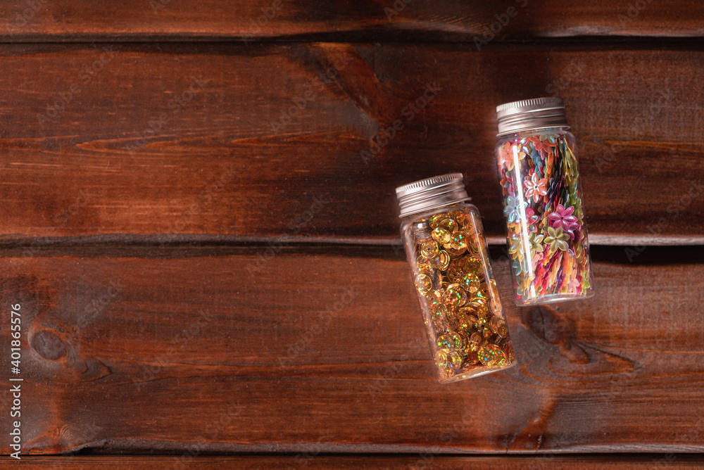 Confetti in the small plastic containers on the wooden table flat lay background with copy space. Confetti in the small plastic containers on the wooden table flat lay background with copy space.