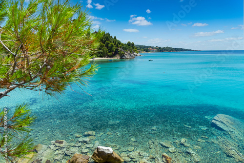 Beautiful bay with beach Aegean Sea on Chalkidiki, Greece, azure blue water under sky with clouds, vacation destination