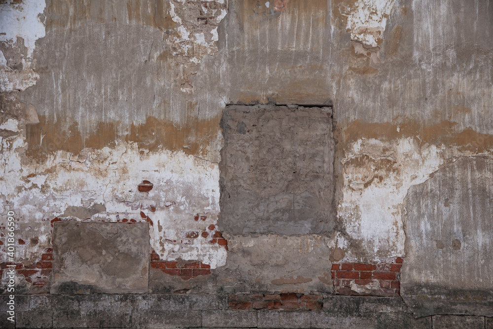 fragment of an old brick wall with concrete plaster and remnants of multicolored paint, grunge, background