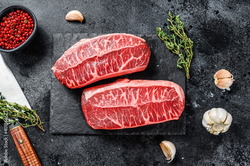 Raw organic meat Twagyu oyster top blade steak. Black background. Top view photo