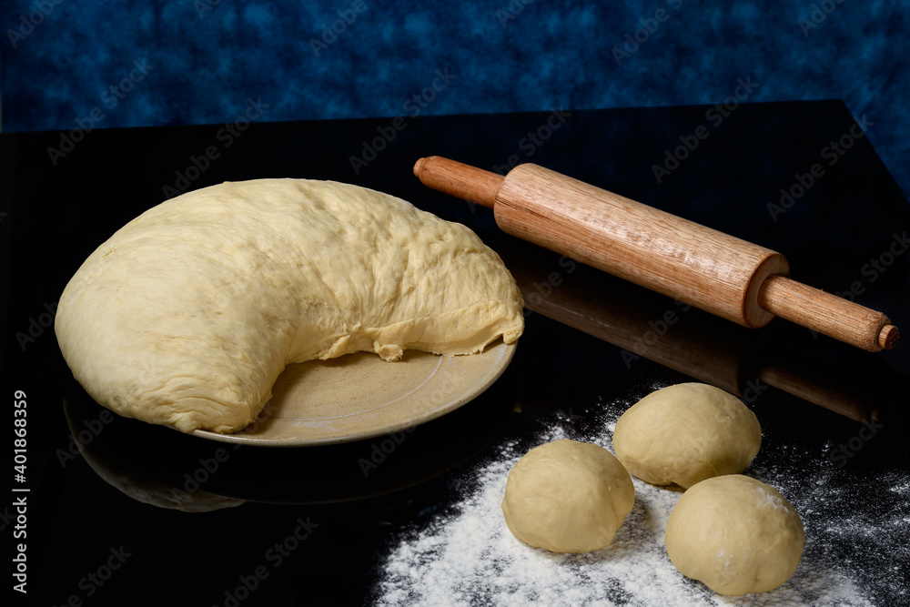 dough for the preparation of bread and cookies, resting on a dark and reflective surface dough for the preparation of bread and cookies, resting on a dark and reflective surface