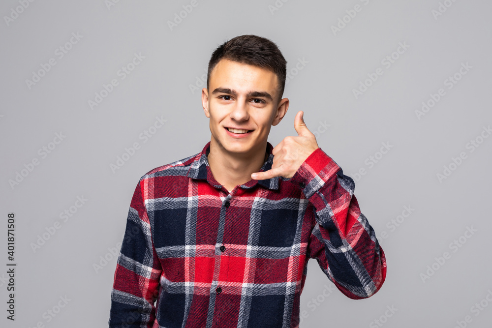 Portrait of smiling young man in casual clothes doing phone gesture like says call me back isolated on grey wall background. People sincere emotions lifestyle concept. Portrait of smiling young man in casual clothes doing phone gesture like says call me back isolated on grey wall background. People sincere emotions lifestyle concept.