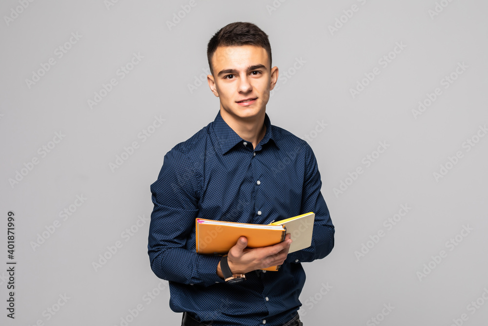 Young Caucasian male student in plaid shirt reading book on grey background Young Caucasian male student in plaid shirt reading book on grey background